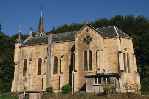 an old brick church with a steeple on a hill at Le Presbytère in Differdange