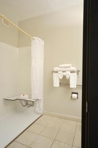 a bathroom with white towels and a shower curtain at Days Inn & Suites by Wyndham Airport Albuquerque in Albuquerque