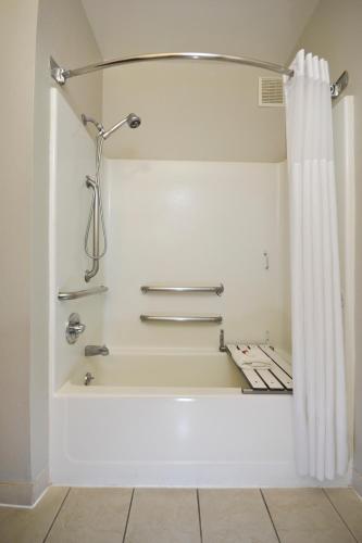 a bathroom with a bath tub with a shower curtain at Days Inn & Suites by Wyndham Airport Albuquerque in Albuquerque