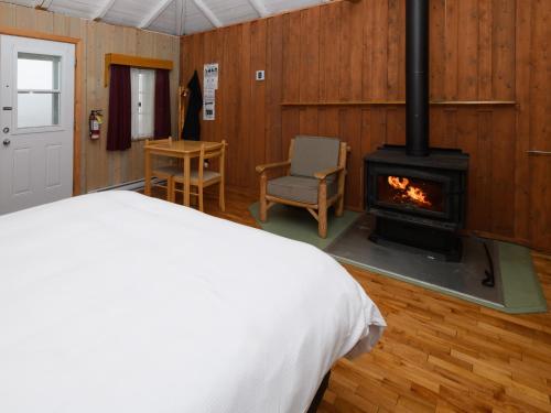 um quarto com uma cama e um fogão a lenha em Au Pic de l'Aurore Motel-Chalets em Percé