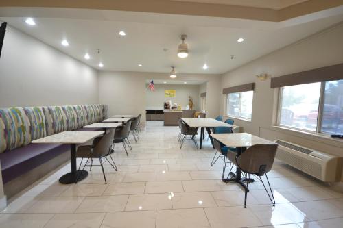 a waiting room with tables and chairs in a restaurant at Days Inn & Suites by Wyndham Airport Albuquerque in Albuquerque