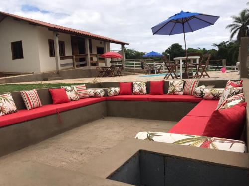a long red couch with pillows and an umbrella at Chalés do Recanto in São João del Rei