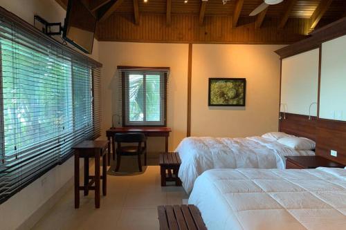 1 Schlafzimmer mit 2 Betten, einem Tisch und einem Schreibtisch in der Unterkunft Luxurious Round Cay in Cayos Cochinos