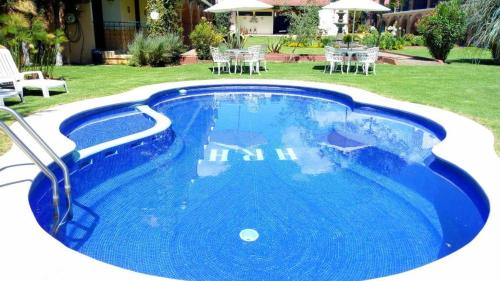 a blue swimming pool with chairs and a table at Hotel Real de Huasca in Huasca de Ocampo