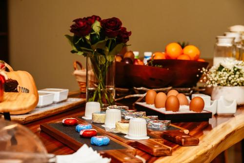 una mesa con huevos y un jarrón de rosas en Santo Thyrso Hotel, en Santo Tirso