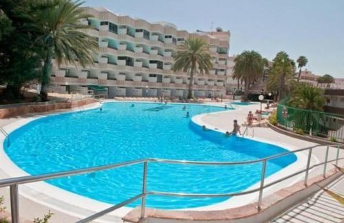 a large blue swimming pool in front of a building at Sweet studio Playa Del Ingles I in Maspalomas