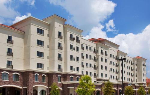 a large white building with trees in front of it at Sonesta ES Suites Baton Rouge University at Southgate in Baton Rouge