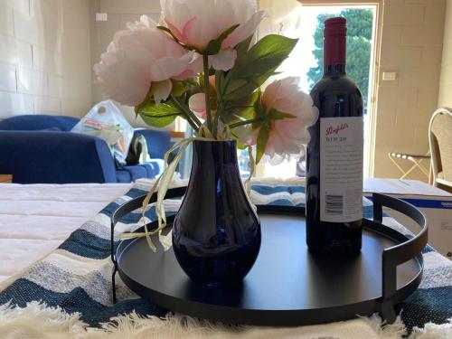 a table with a bottle of wine and a vase with flowers at Apollo Motel Parkes in Parkes