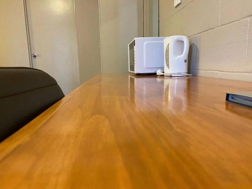 a white microwave sitting on top of a wooden floor at Apollo Motel Parkes in Parkes