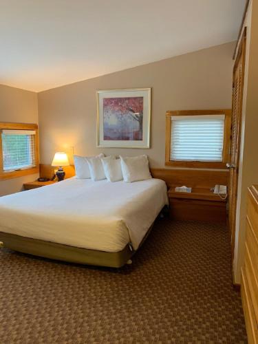 a bedroom with a large white bed with two windows at Pocono Villas Resort in East Stroudsburg