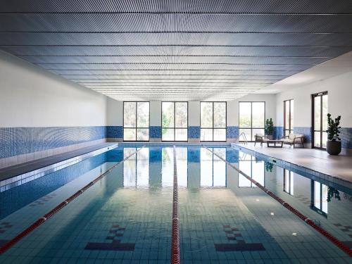 uma grande piscina com azulejos azuis e janelas em Hidden Valley Resort em Wallan