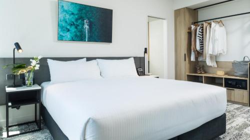 a bedroom with a large white bed and a desk at Oaks Cairns Hotel in Cairns