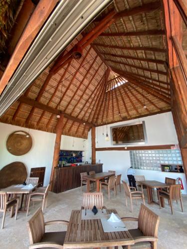 a restaurant with tables and chairs and a straw roof at Casa del Puerto by MIJ - Beachfront Hotel in Puerto Morelos