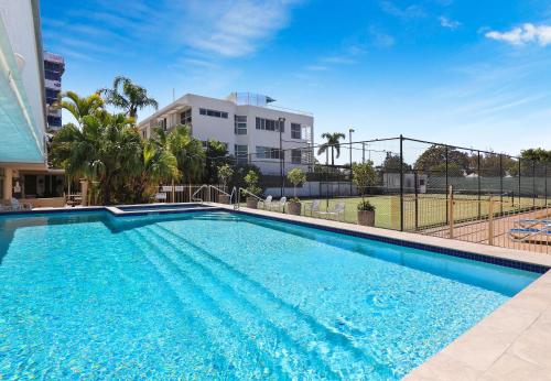 a swimming pool in front of a building at Elouera Tower in Maroochydore