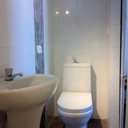 a bathroom with a white toilet and a sink at Machupicchu Guest House in Machu Picchu