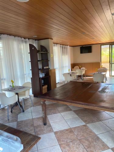 Habitación con mesas, sillas y suelo de madera grande. en Flat Pancetti, en Belo Horizonte