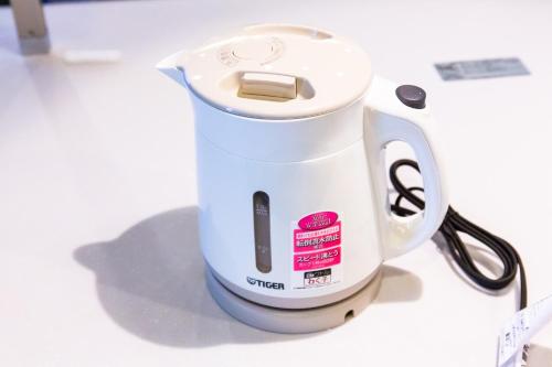 a white coffee maker sitting on a table at Rizo Zaizen Hotel in Ginowan
