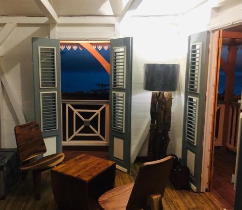 a room with a table and chairs and a window at Habitation Baliache - Maison créole avec jardin privatif, plage à 200m in Deshaies