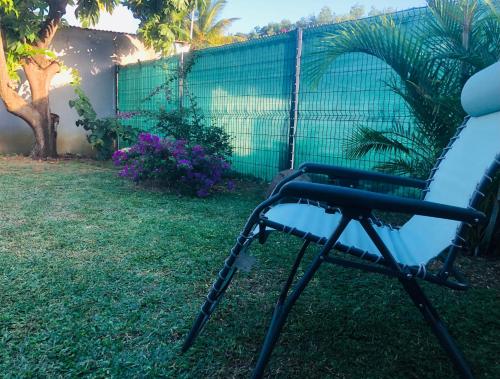 a chair sitting in the grass in a yard at Habitation Baliache - Maison créole avec jardin privatif, plage à 200m in Deshaies