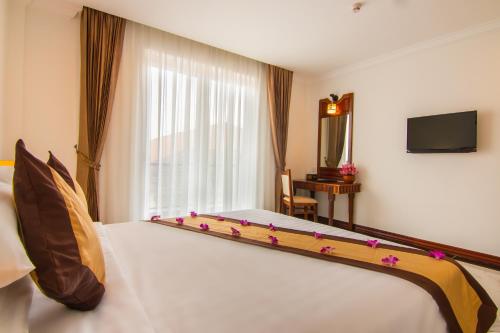 a bedroom with a large white bed with flowers on it at Glorious Hotel & Spa in Kompong Thom