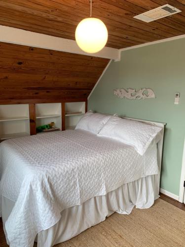 a bedroom with a white bed with a wooden ceiling at Salty Poodle Cottage in Freeport