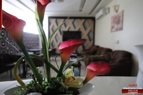 a vase filled with red flowers on a table at لافينا حائل للاجنحة الفندقية in Hail