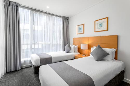 Habitación de hotel con 2 camas y ventana en Quest Southbank, en Melbourne