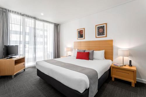 a hotel room with a bed, chair, and nightstand at Quest Southbank in Melbourne