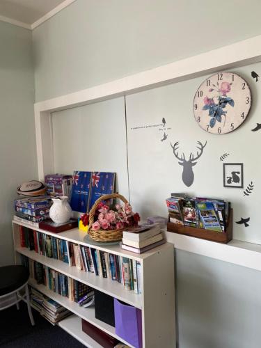 a book shelf with books and a clock on a wall at National Park Alpine Lodge in National Park