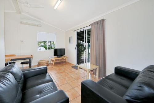 a living room with a black leather couch and a television at Cane Village Holiday Park in Bundaberg