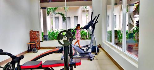 a gym with three treadmills and a woman in a pink dress in at Glorious Hotel in Kompong Thom