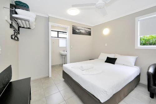 a bedroom with a large white bed and a desk at Cane Village Holiday Park in Bundaberg