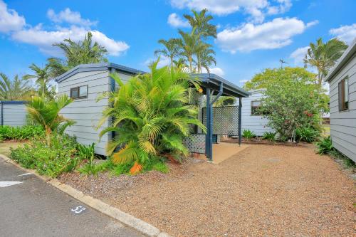 a house with a gate and a palm tree at Cane Village Holiday Park in Bundaberg