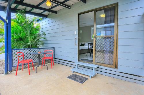 a patio with two chairs and a table and a bench at Cane Village Holiday Park in Bundaberg