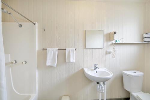 a white bathroom with a sink and a toilet at Cane Village Holiday Park in Bundaberg