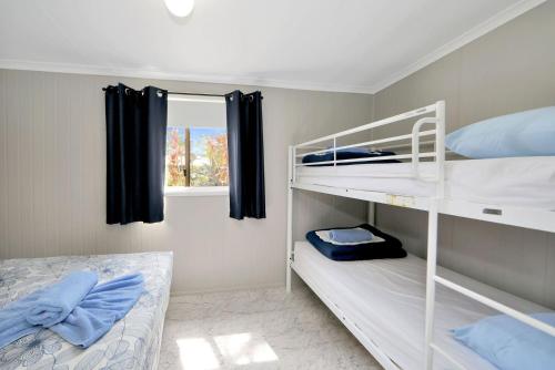 a bedroom with two bunk beds and a window at Cane Village Holiday Park in Bundaberg