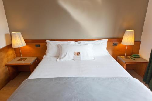um quarto com uma grande cama branca e 2 candeeiros em Hotel Ai Gelsi em Codroipo