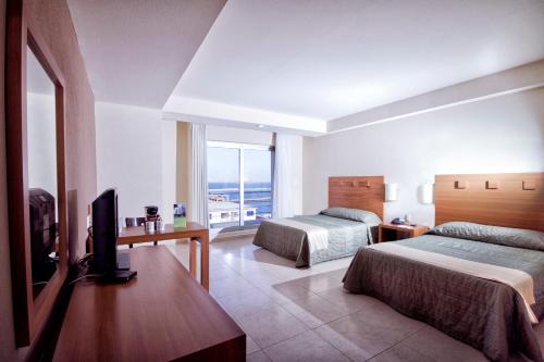 Habitación de hotel con 2 camas y TV en Balaju Hotel & Suites, en Veracruz