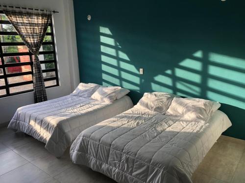 twee bedden in een kamer met schaduwen aan de muur bij Hermosa casa campestre CASARENA "un oasis en el llano" in Villavicencio