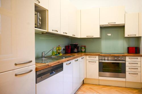 eine Küche mit weißen Schränken und einer Spüle in der Unterkunft Bright Suite Universitaet Wien in Wien