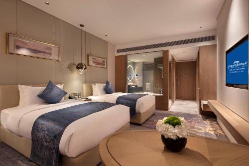 a hotel room with two beds and a flat screen tv at Howard Johnson by Wyndham Jimei Lake Plaza Xiamen in Xiamen
