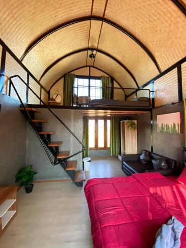 a bedroom with a large red bed and a staircase at ข้าวทุ่งเบ็ญจาโฮมสเตย์ in Ban Hat Phang