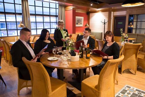 een groep mensen die rond een tafel in een restaurant zitten bij Finlandia Hotel Isovalkeinen in Kuopio