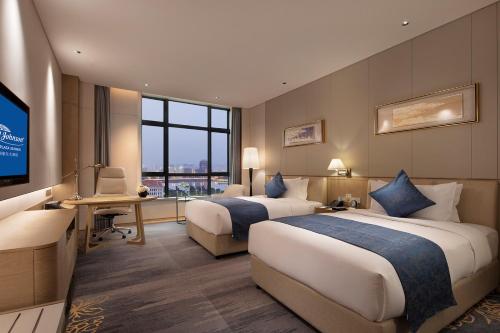 a hotel room with two beds and a television at Howard Johnson by Wyndham Jimei Lake Plaza Xiamen in Xiamen
