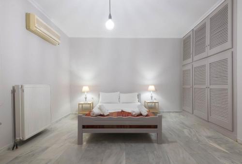 ein weißes Zimmer mit einem Bett und zwei Lampen in der Unterkunft The Lofos Studios in Alykes