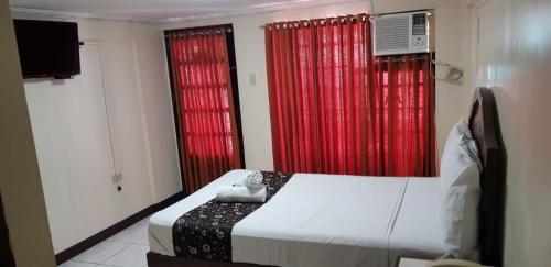 a bedroom with red curtains and a bed and a tv at Grand Traveler Suite Inc in Manila