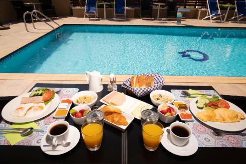 a table with food and drinks next to a swimming pool at Hotel Olympos in Leptokaria