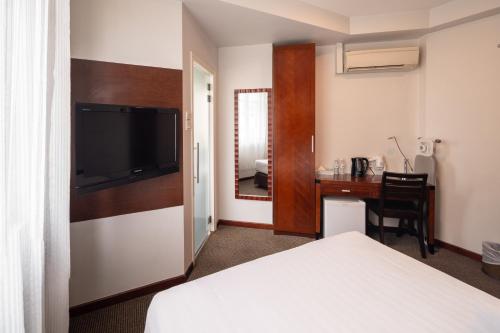 シンガポールにあるThe Quay Hotel West Coastのベッドとデスクが備わるホテルルームです。