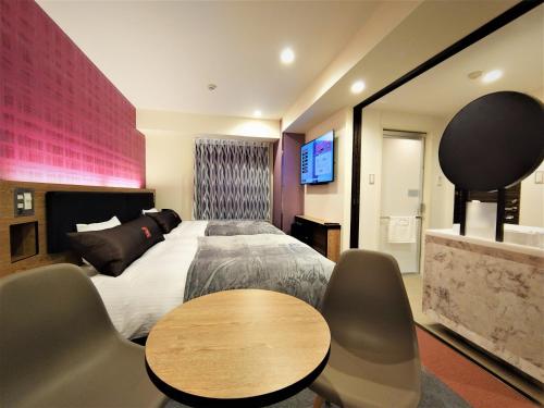 a bedroom with a bed and a table and chairs at Green Rich Hotel Nagoya Nishiki (Artificial hot spring Futamata Yunohana) in Nagoya