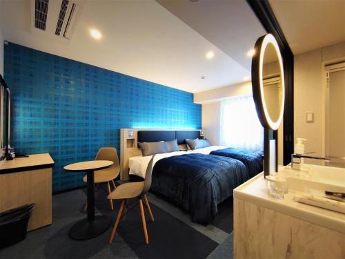 a bedroom with a bed and a blue wall at Green Rich Hotel Nagoya Nishiki (Artificial hot spring Futamata Yunohana) in Nagoya